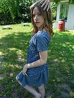 Clothed babe in blue floral dress poses barefoot solo tease in sunny garden