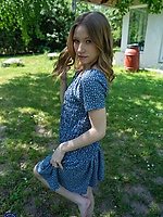 Clothed babe in blue floral dress poses barefoot solo tease in sunny garden