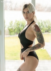Elegant blonde model with tattoos undresses by the pool
