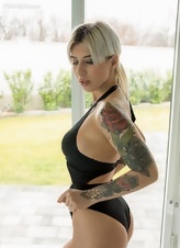 Elegant blonde model with tattoos undresses by the pool