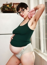 Pregnant MILF with glasses shows off her bush and saggy tits