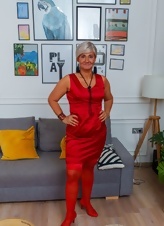 A naked older woman looks gorgeous in a red dress, her devilish thoughts are perfect for porn pictures