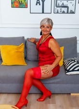 A naked older woman looks gorgeous in a red dress, her devilish thoughts are perfect for porn pictures