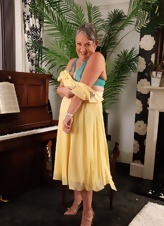 Mature woman in yellow dress fondling slightly hairy pussy